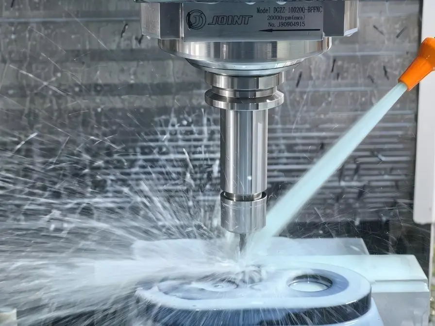 3-axis CNC milling machine performing precision cutting with active coolant on a metal part.