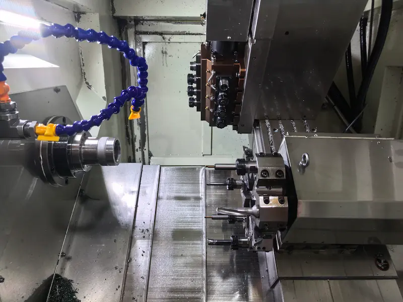 4-axis CNC milling center machining a cylindrical metal component using a rotary A-axis.